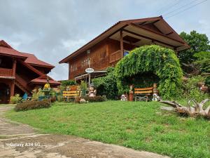 a house with a yard with benches in front of it at ริมเมืองโฮมสเตย์ in Phrae