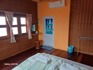 een slaapkamer met een bed, een raam en een deur bij ริมเมืองโฮมสเตย์ in Phrae