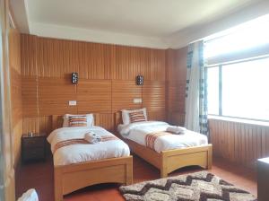 2 letti in una camera con pannelli in legno di Hotel Tayatha a Tawang