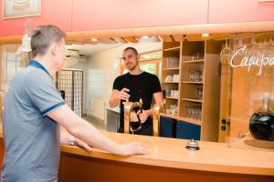 a man standing at a counter talking to a customer at Aktiv-Hotel Stock & Stein in Königstein an der Elbe