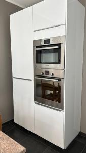 a white kitchen with an oven in a white cabinet at Casa Polizzi - Maison entière in Fontaine-lʼÉvêque