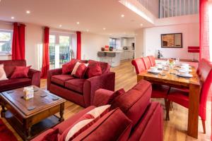 een woonkamer met rode meubels en een tafel bij Cariad - Spacious 3 bed, group getaway Luxury Cottage with Private Hot Tub in Denbigh