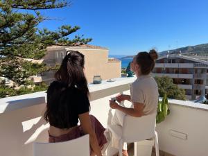 Due donne sedute su un balcone che guardano l'oceano di Don Carlo Tropea a Tropea