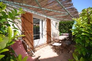 un patio avec une pergola en bois et une table et des chaises dans l'établissement Le Clos des Galéjades, à Porquerolles