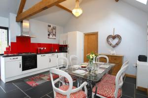 a kitchen with a table and chairs and a kitchen with red at Woodshed Cottage in Ashbourne