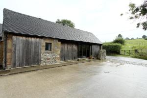 an old stone building with a driveway in front of it at Woodshed Cottage in Ashbourne