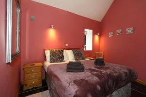 a bedroom with red walls and a large bed at Woodshed Cottage in Ashbourne