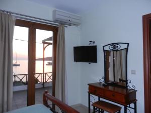 a bedroom with a mirror and a dresser and a television at ANEMOESSA APTS in Livadia