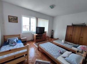 a living room with three beds and a flat screen tv at Trosoban stan u Zenici in Zenica