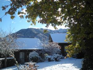a house covered in snow with mountains in the background at Forest Peak Motel in Hanmer Springs