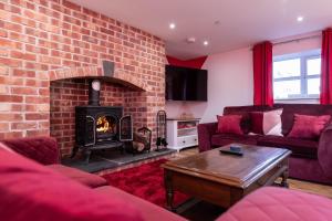 een woonkamer met een bakstenen muur en een open haard bij Cariad - Spacious 3 bed, group getaway Luxury Cottage with Private Hot Tub in Denbigh