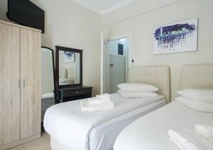 Habitación blanca con 2 camas y espejo. en MEDLUXE EASY ACROPOLIS APARTMENT!, en Atenas