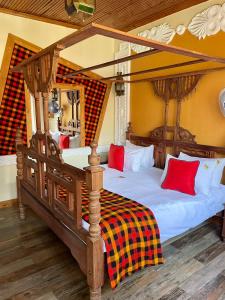 a bedroom with a four poster bed with red pillows at Parklands Shade Hotel in Nairobi