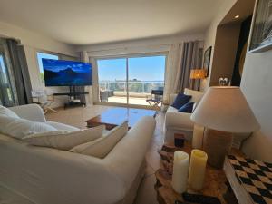 a living room with white furniture and a large window at Villa Les Voiles in Cannes