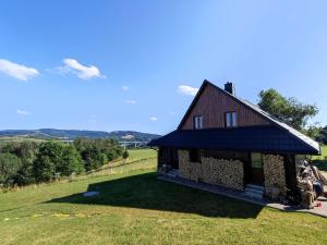 una pequeña casa en una colina con un campo verde en Chata BO Hrčava en Hrčava