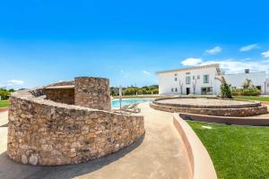 a stone wall next to a swimming pool and a building at Masseria Sant'Eleuterio in Collepasso