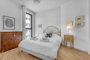 a white bedroom with a large bed and a window at Rosario - Joli T3 climatisé dans Toulouse in Toulouse