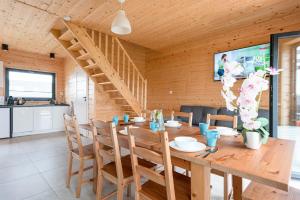 a dining room with a wooden table and a staircase at OSADA JANTAr 3 DOM 70m2 in Jantar