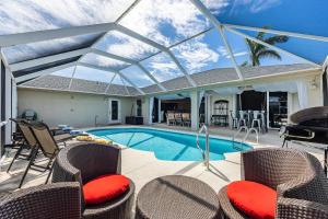 a patio with a swimming pool with chairs and a glass roof at Villazo Ann, Cape Coral in Cape Coral