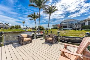 a wooden deck with chairs and a boat on the water at Villazo Ann, Cape Coral in Cape Coral