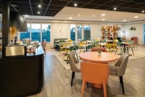 a restaurant with tables and chairs in a cafeteria at Sure Hotel by Best Western Rochefort-sur-Mer in Tonnay-Charente