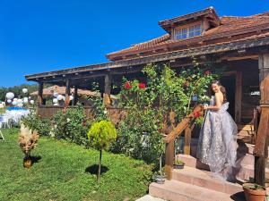 a woman in a dress standing in front of a house at Rustic House Radovic in Knić +12 photos
