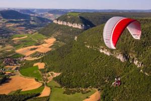 un paracaídas rojo y blanco volando sobre una montaña en T2 lumineux hypercentre, en Millau