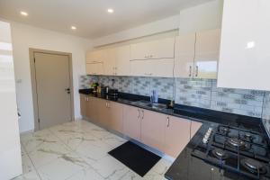 a kitchen with white cabinets and a black counter top at Luxury 3br Ensuite Apt in Prestigious Nyali in Mombasa