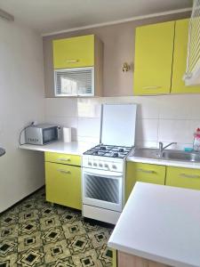 una cucina con armadi gialli e piano cottura. di TANI apartament a Łódź