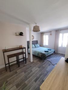um quarto com uma cama, uma secretária e uma mesa em Chambre indépendante Au Relais Normand em Cormeilles