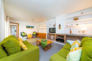 uma sala de estar com dois sofás verdes e uma lareira em Can Roig Loft em Colonia de Sant Pere