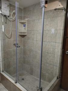 y baño con ducha y puerta de cristal. en Hostal Turístico El Cajamarquez, en Lima