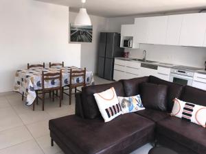 a living room with a brown couch and a kitchen at Les PECHERS N 2 MAISON DE 87 m2 à 5mn de La Rochelle de l'île de ré et des plages in La Genilliere