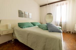 デセンツァーノ・デル・ガルダにあるLa Chicca sui Tetti Centro&Lago By Case al Lagoのベッドルーム1室(緑の枕と鏡付きのベッド1台付)