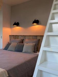 a bedroom with a bed with two pillows and two lights at Stijlvol huisje met veranda! Tuynloodz C in Beers