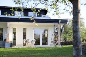 a white house with a black roof and chairs at Stijlvol huisje met veranda! Tuynloodz C in Beers