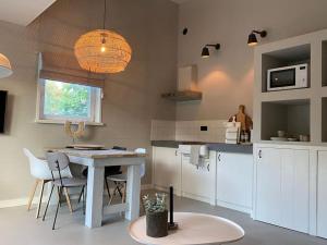 a kitchen with a table and some chairs and a table at Stijlvol huisje met veranda! Tuynloodz C in Beers