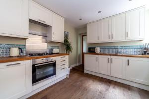 a white kitchen with white cabinets and wooden floors at The Queenstown Villa in London