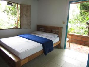 ein Schlafzimmer mit einem Bett mit einer blauen Decke darauf in der Unterkunft Alojamiento rural pájaros y flores in Los Andes
