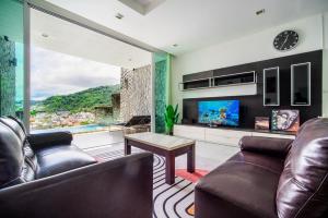 a living room with a couch and a table and a tv at patong villa2：四卧泳池别墅/两个海景房/近班赞酒吧街 in Patong Beach
