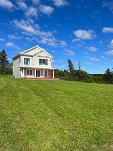 una casa blanca en un campo con un gran campo de hierba en Bela Vista Getaway - PEI Tourism License #1201185, en Park Corner