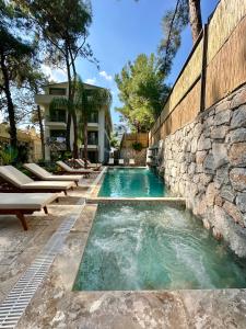 een zwembad met ligstoelen en een stenen muur bij Esmahan Forest and Pool by Zehra Suites in Marmaris