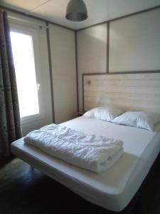 1 cama grande con sábanas blancas y ventana en Mes deux Gîtes de l'Ocre en Villars