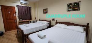 two beds in a room with white sheets at Dayview Tourist Home in Tagbilaran City
