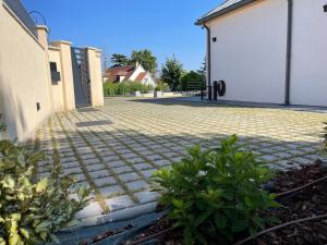 a brick driveway with a white building and some plants at La Villa Perchée, Appartements Élégants, sauna Privé, sport, terrasses et Vue Panoramique, Parking protégé, proche PARIS in Saint-Prix +81 photos