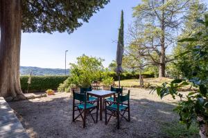 a table and chairs sitting in the shade of a tree at Fattoria la Gigliola - Il Frantoio in Montespertoli