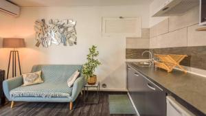 a kitchen with a couch and a chair in a room at 1A - Chambres et Appartements au calme - Centre St Denis - Barachois in Saint-Denis