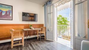 Habitación con mesa y balcón con TV. en 1A - Chambres et Appartements au calme - Centre St Denis - Barachois, en Saint-Denis