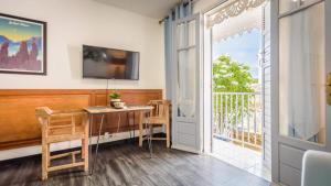 a room with a table and a balcony with a television at 1A - Chambres et Appartements au calme - Centre St Denis - Barachois in Saint-Denis