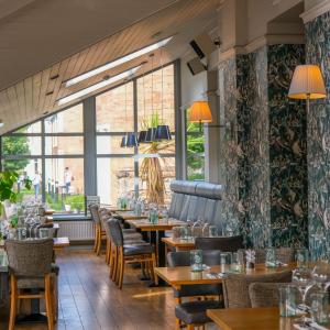 インバネスにあるGlen Mhor Hotel at Uile-bheist 'Brewstillery'のテーブルと椅子、大きな窓のあるレストラン